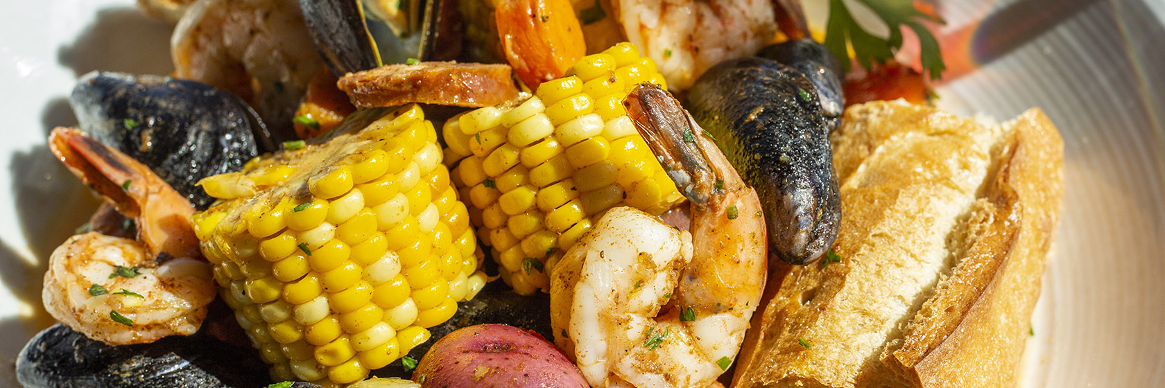 Close-up of Seafood Boil entree with sausage, shrimp, corn, mussels and red potatoes