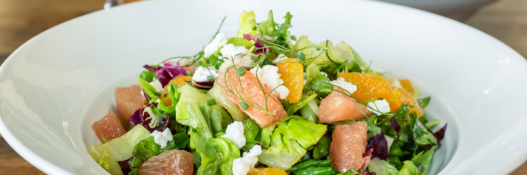 Salad with fresh citrus slices in round bowl at The Pearl Restaurant.